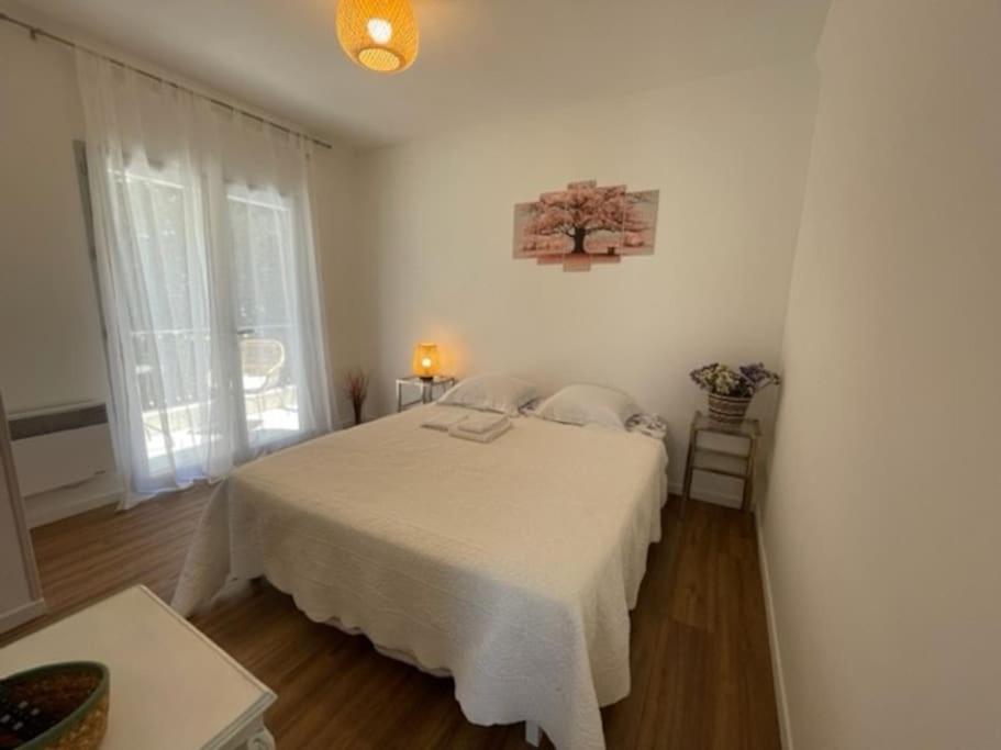 a white bedroom with a white bed and a window at Superbe studio à Juan les pins in Juan-les-Pins