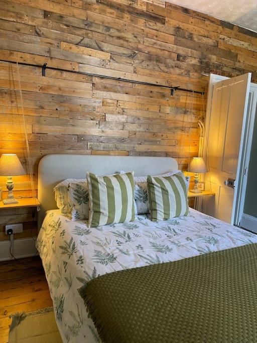 een slaapkamer met een bed met een houten muur bij Cosy 2 bed flat in Crickhowell in Crickhowell