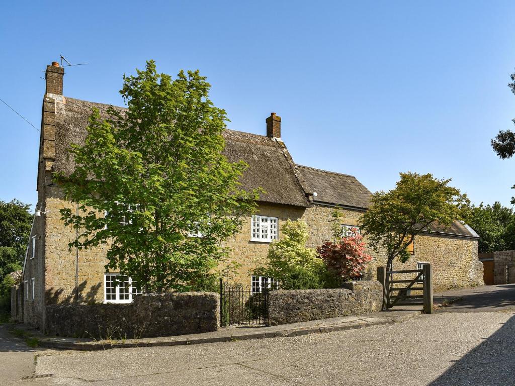 an old stone building with a tree in front of it at Lower Barrowfield Farm in Beaminster