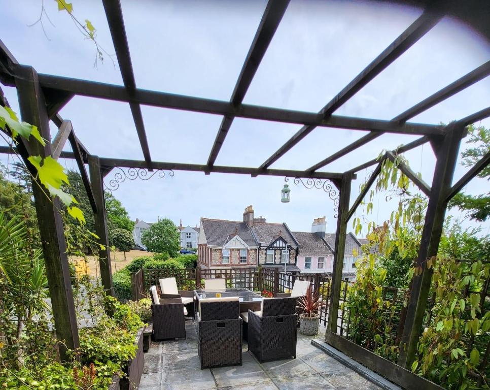 a pergola with a table and chairs in a garden at Aremo Room 1 in Torquay