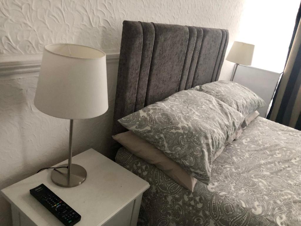 a bedroom with a bed with a lamp and a pillow at AC Lounge 125 in Rochford