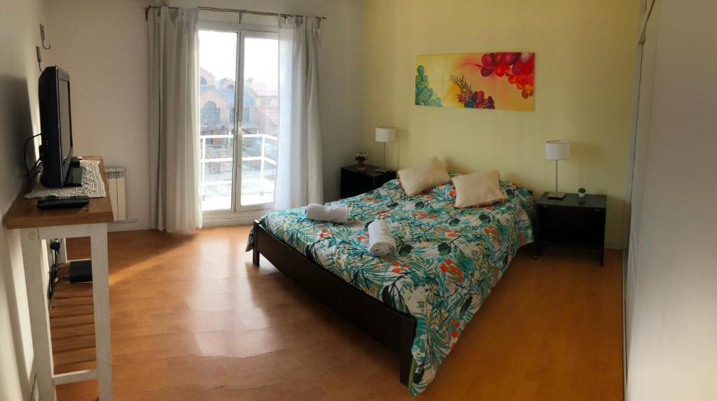 Un dormitorio con una cama y un televisor y una ventana. en Departamento Mailin, en Puerto Madryn