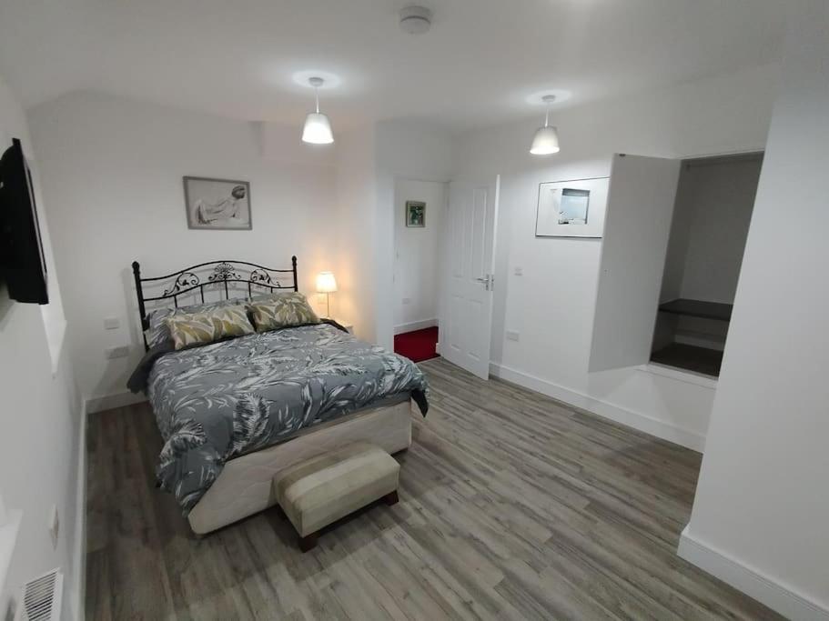 a bedroom with a bed in a white room at Charming Studio Flat with Parking in Enfield