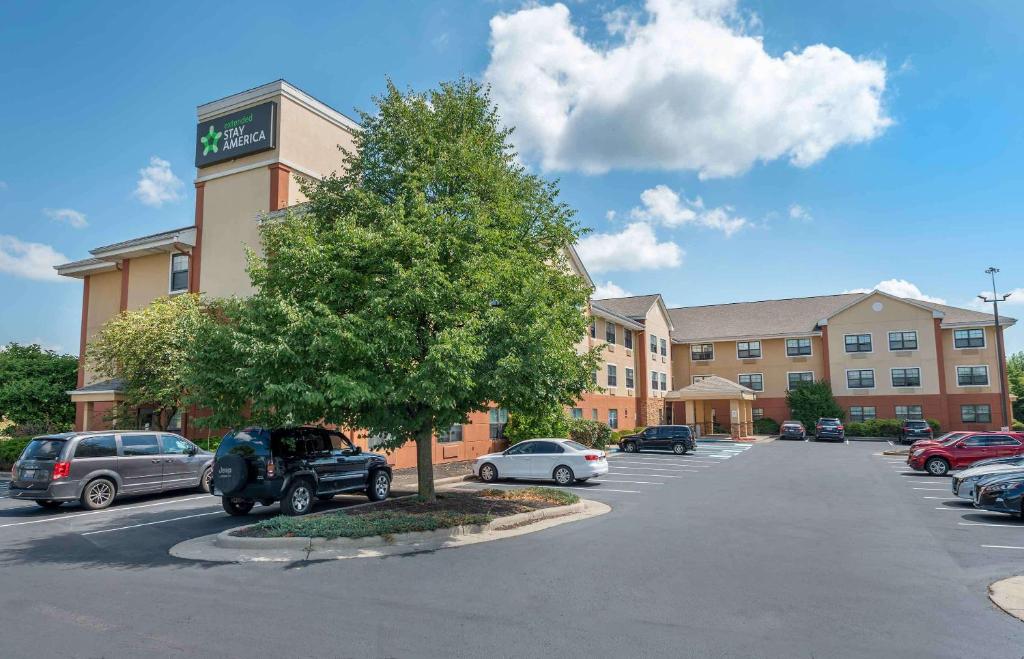 Extended Stay America Suites - Dayton - North في دايتون: مبنى فيه سيارات متوقفة في موقف للسيارات