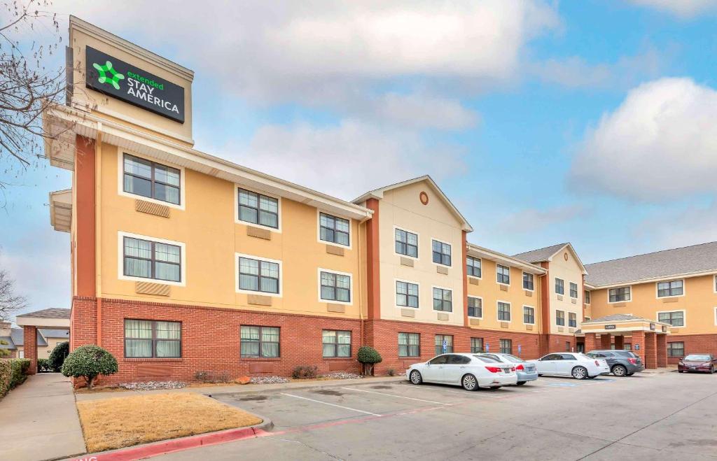 un bâtiment d'hôtel avec des voitures garées dans un parking dans l'établissement Extended Stay America Suites - Fort Worth - City View, à Fort Worth