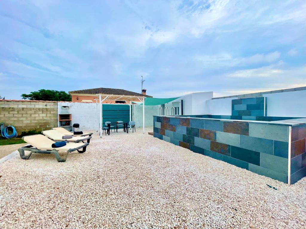 eine Terrasse mit Stühlen und Tischen sowie ein Gebäude in der Unterkunft Casita de la coquina in Chiclana de la Frontera