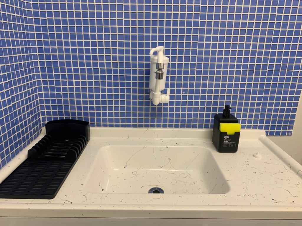 baño de azulejos azules con bañera y dispensador de jabón en Kitnet Penha CEFAN ADVEC en Río de Janeiro