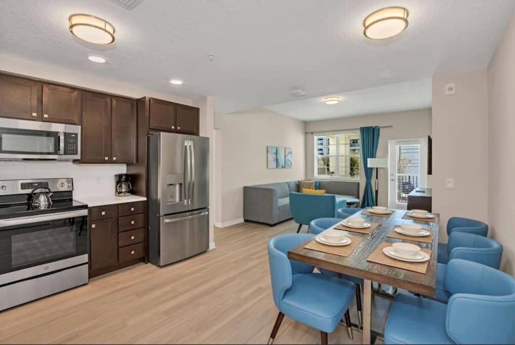 a kitchen and dining room with a table and blue chairs at Modern 3B2b Codon in Vista Cay, near Convention Center Universal, See World, Disney in Orlando