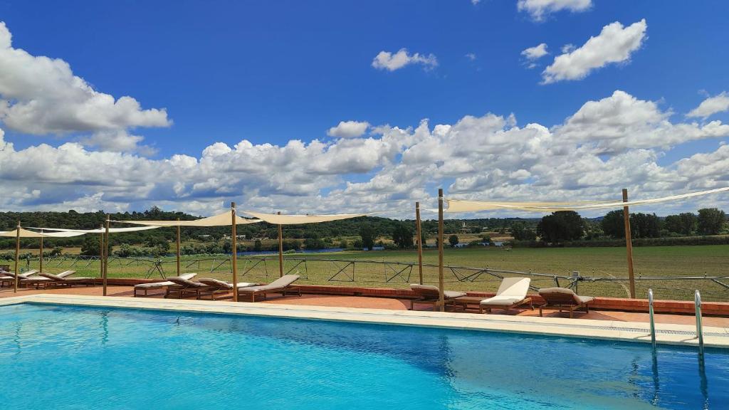 uma piscina com espreguiçadeiras e vista para um campo em Quinta das Arribas em Abrantes