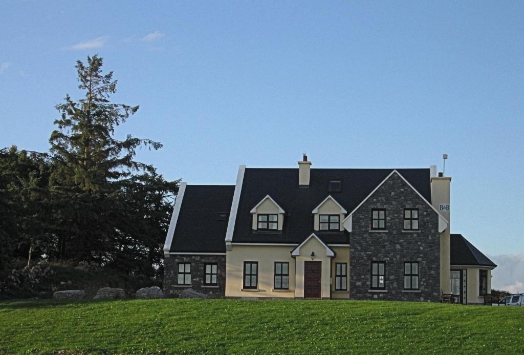 a large house on a hill with a green field at Kinvara Inn B&B in Kinvara
