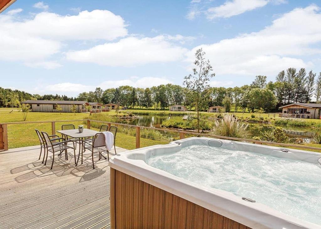 a hot tub on a deck with a table and chairs at Cedar Retreats in Masham