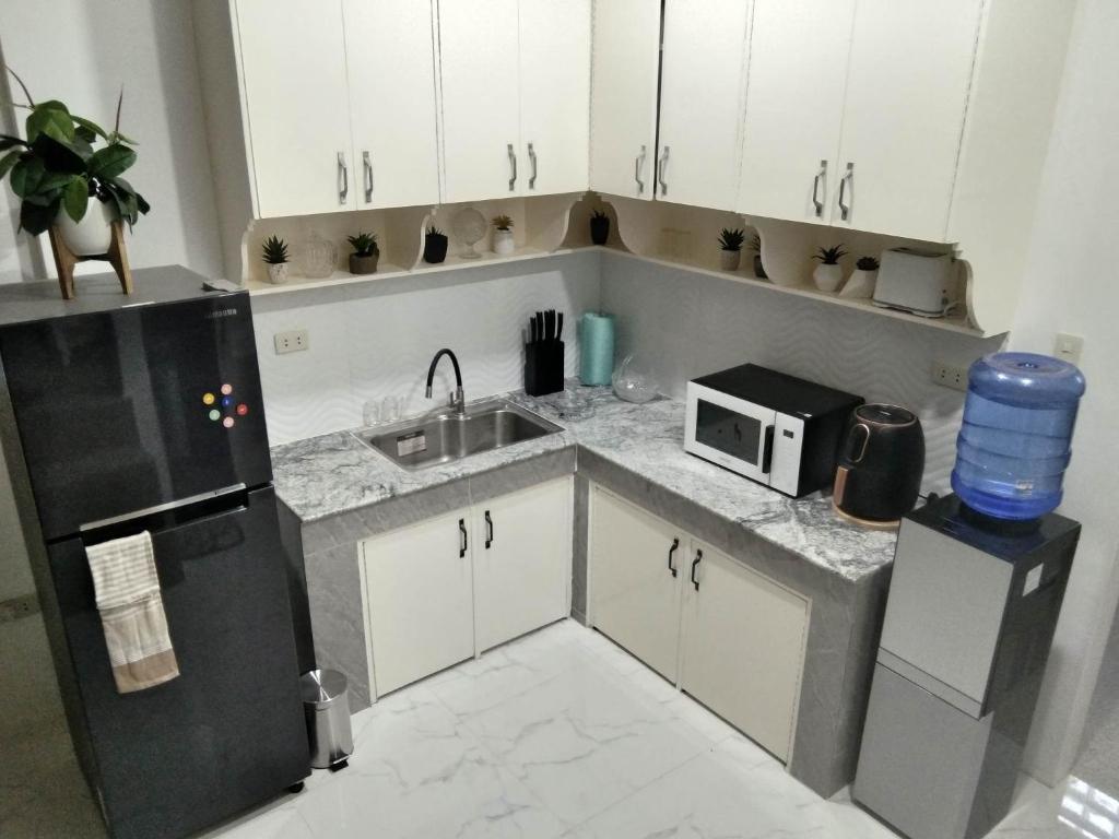 a kitchen with a refrigerator and a sink and a microwave at 80Square Guest House in Gingoog