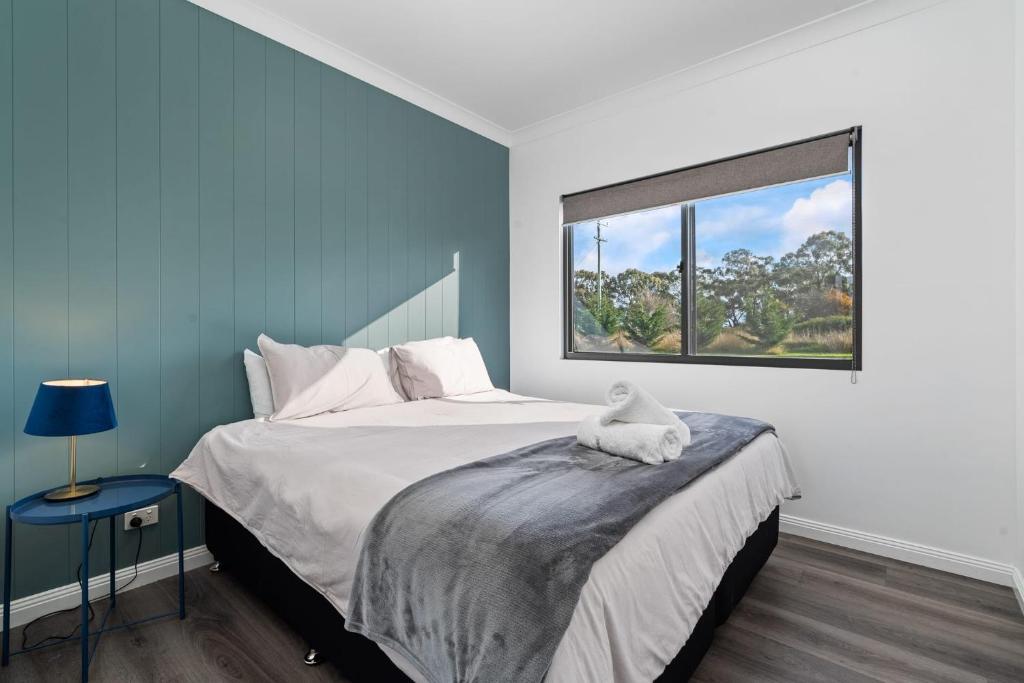 a bedroom with a large bed and a window at Glenowrie Cottage - 1 King 2 Singles Near Cadia in Millthorpe