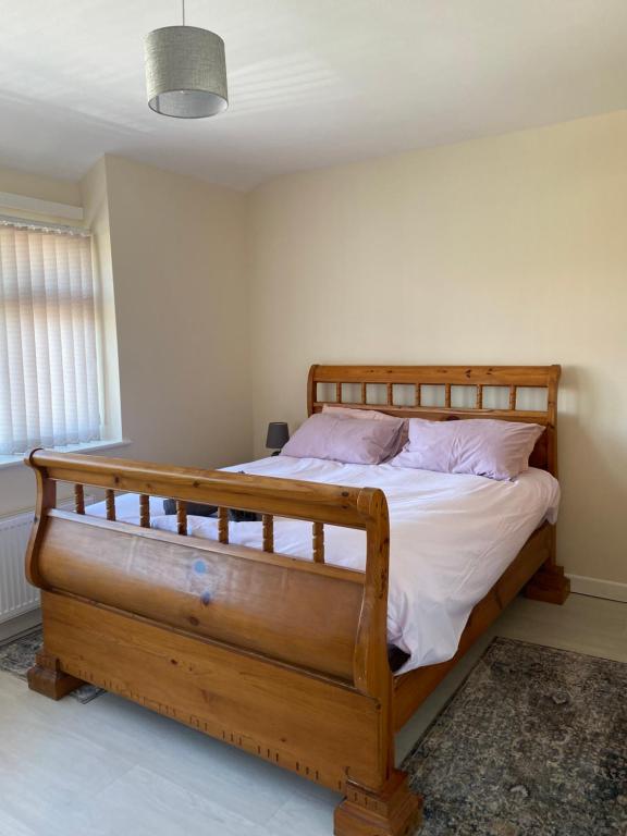 a bedroom with a wooden bed with white sheets and pink pillows at Greenwood in Manchester