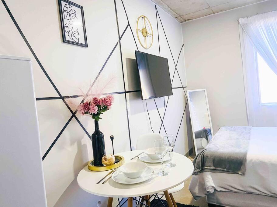 a small white table with a vase of flowers on it at Cozy escape bachelor in Maboneng + uncapped WI-FI. in Johannesburg