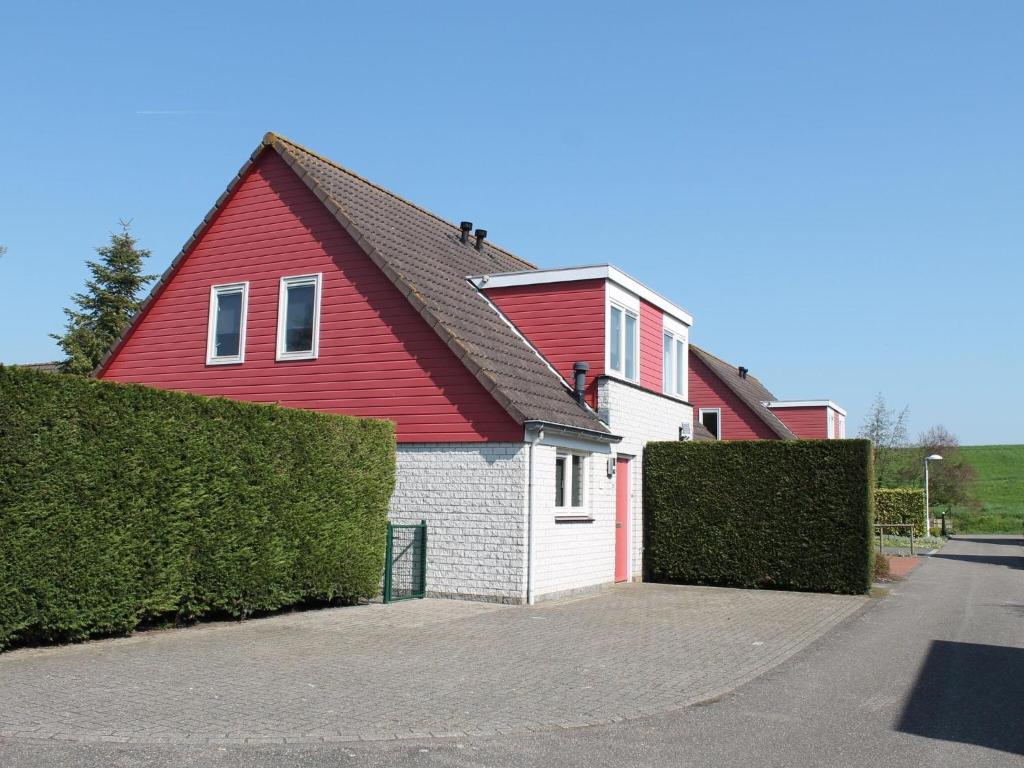 ein rotes und weißes Haus mit einer Garage in der Unterkunft Nice holiday home with garden, on a holiday park 200m from the beach in Wemeldinge