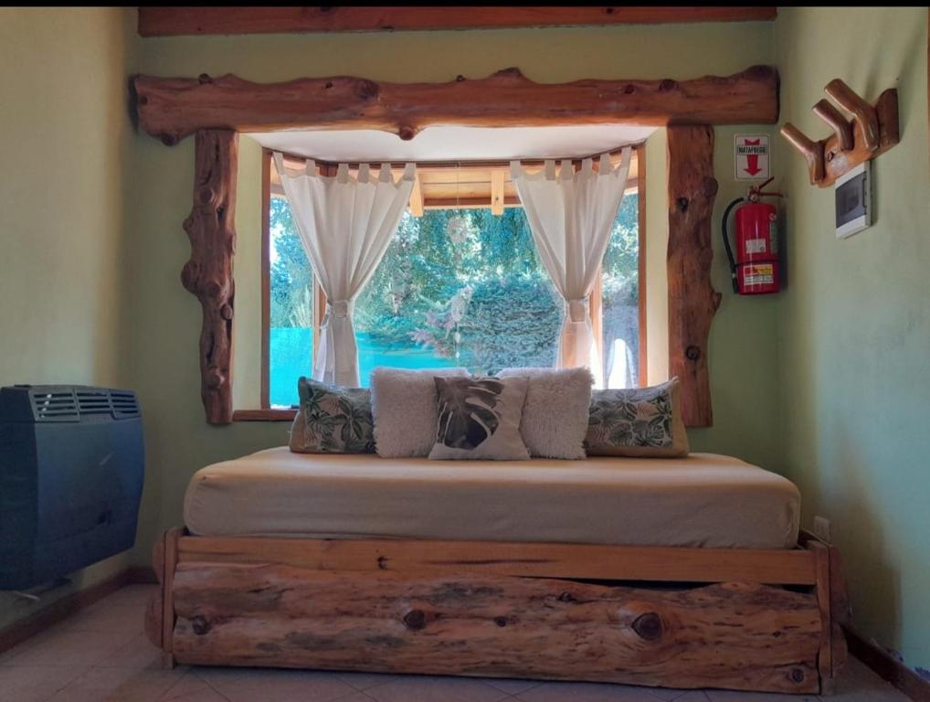 1 dormitorio con 1 cama y ventana grande en Tierras del Sur en Villa La Angostura
