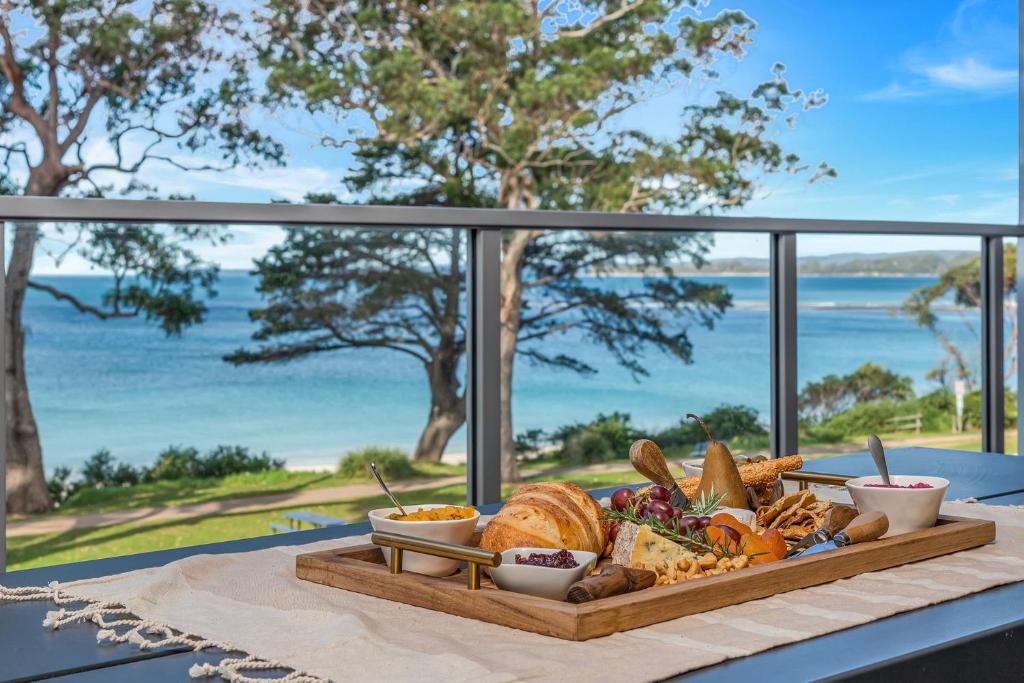 a tray of food on a table with a view of the ocean at The View by Experience Jervis Bay in Huskisson