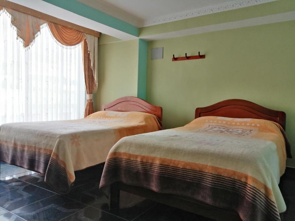two beds in a room with green walls and a window at HOTEL LA 7MA AZUL in Pasto