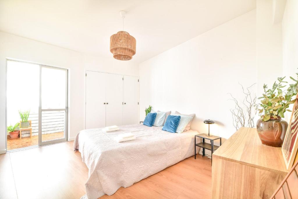 a white bedroom with a large bed with blue pillows at Casa da Raposa by MOJE Holiday in Lagos