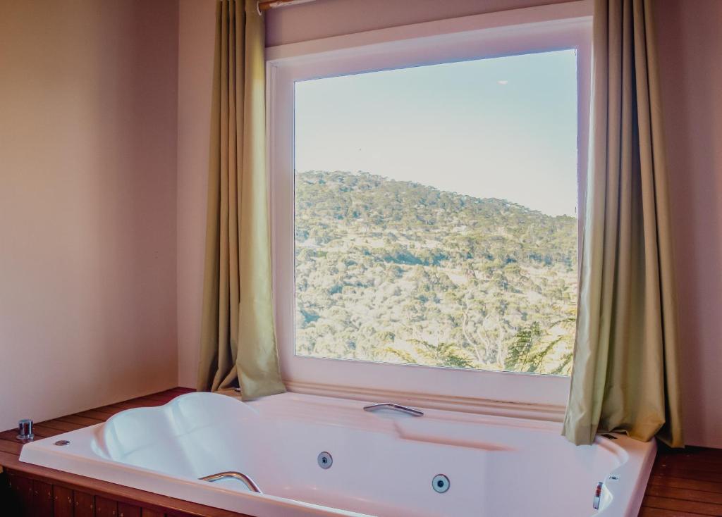 a bath tub in a room with a large window at Pousada Lago da Colina in Urubici