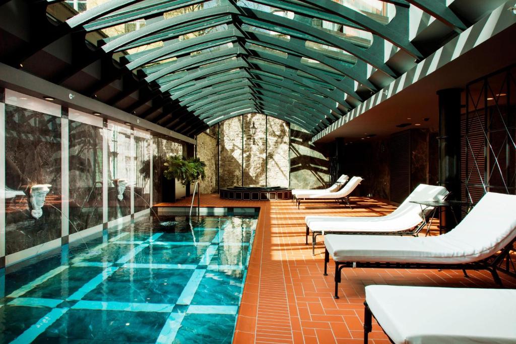 a swimming pool with chairs and a ceiling at Hotel Telegraaf, Autograph Collection in Tallinn