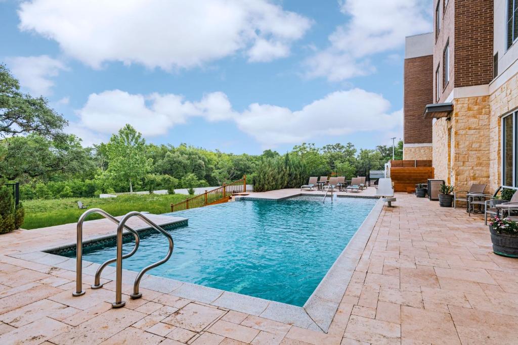 einen Pool mit einer Terrasse mit Stühlen und Tischen in der Unterkunft Residence Inn by Marriott Austin Southwest in Austin