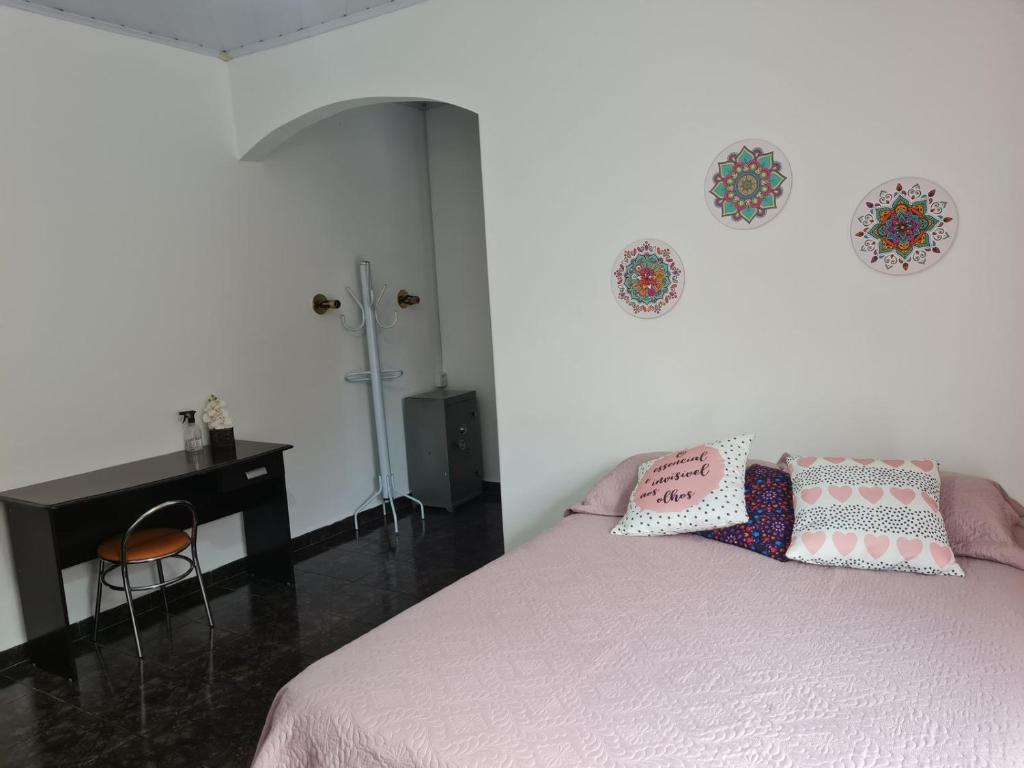 1 Schlafzimmer mit einem Bett mit einem Schreibtisch und 2 Kissen in der Unterkunft Casa com quarto e suíte in São Miguel Arcanjo