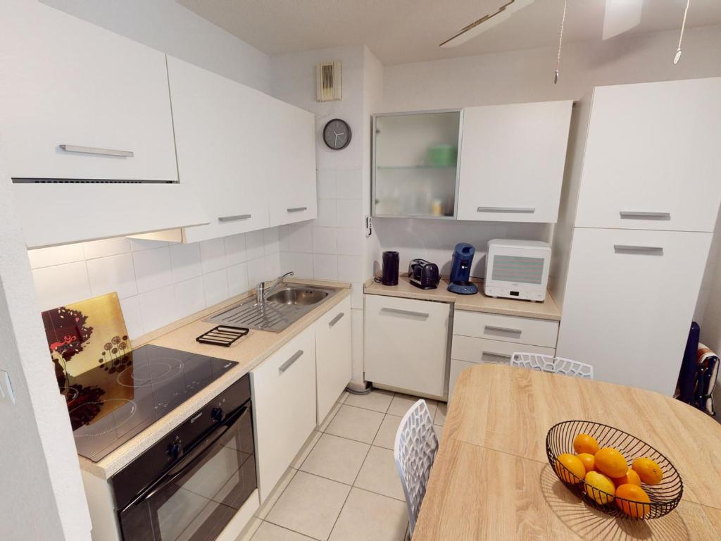 a kitchen with white cabinets and a table with a bowl of fruit at Appartement Menton, 2 pièces, 4 personnes - FR-1-196-336 in Menton