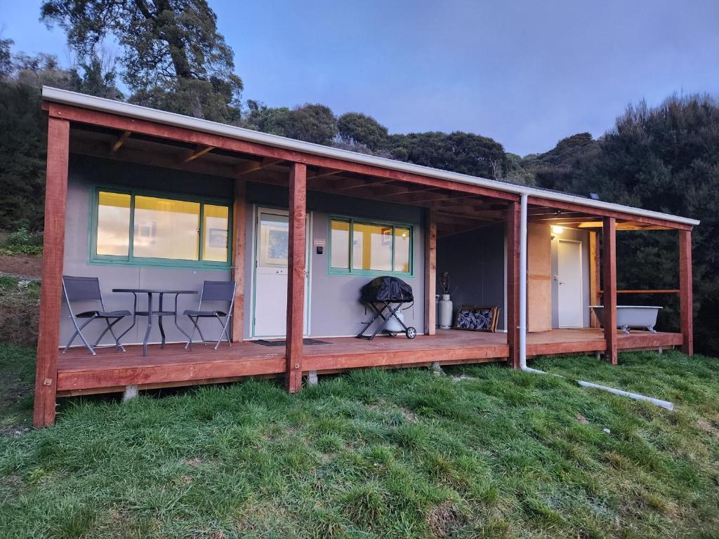 a wooden cabin with a table and chairs in a field at Glenwood Akaroa Bush Retreat - Kanuka Hut in Akaroa