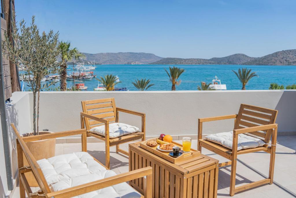 2 sillas y una mesa en un balcón con vistas al océano en Elounda Helios Luxury Apartment with Rooftop Jacuzzi en Elounda