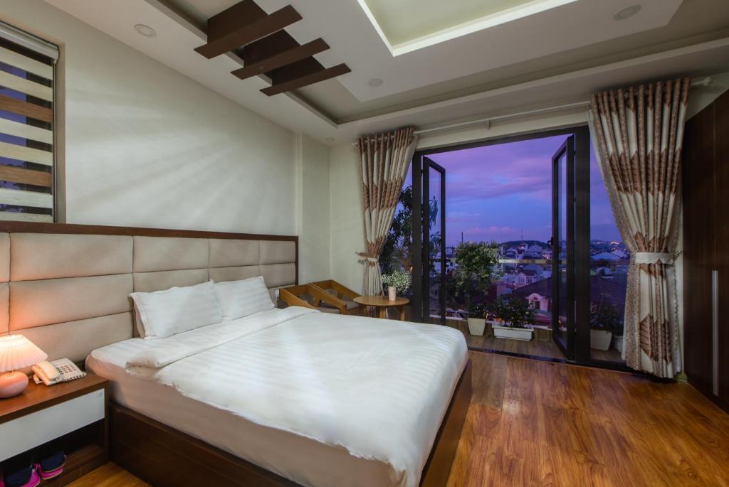 a bedroom with a large bed and a large window at Tasme Hotel in Da Lat