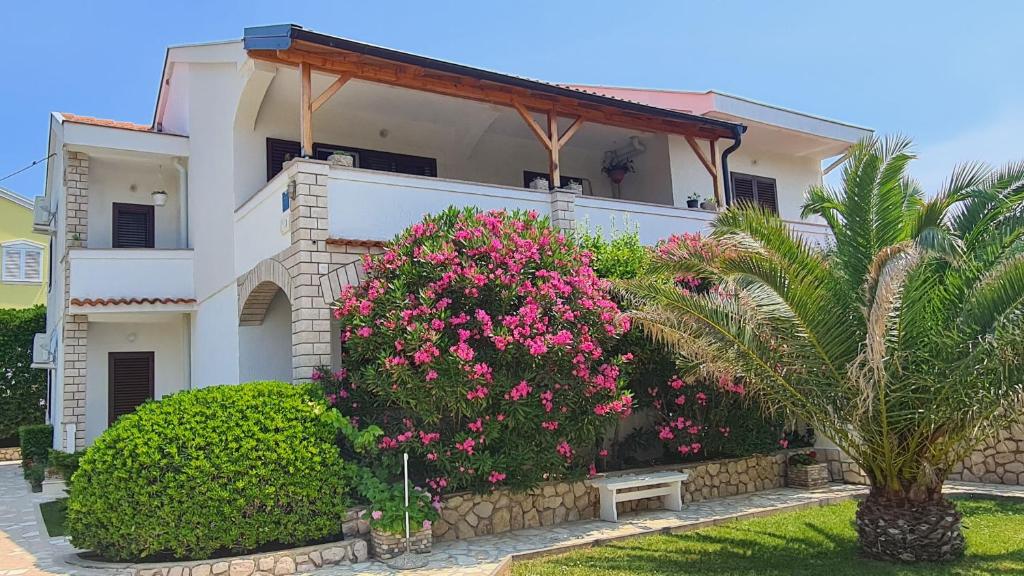 a white house with pink flowers in front of it at Apartments Ivo in Pag