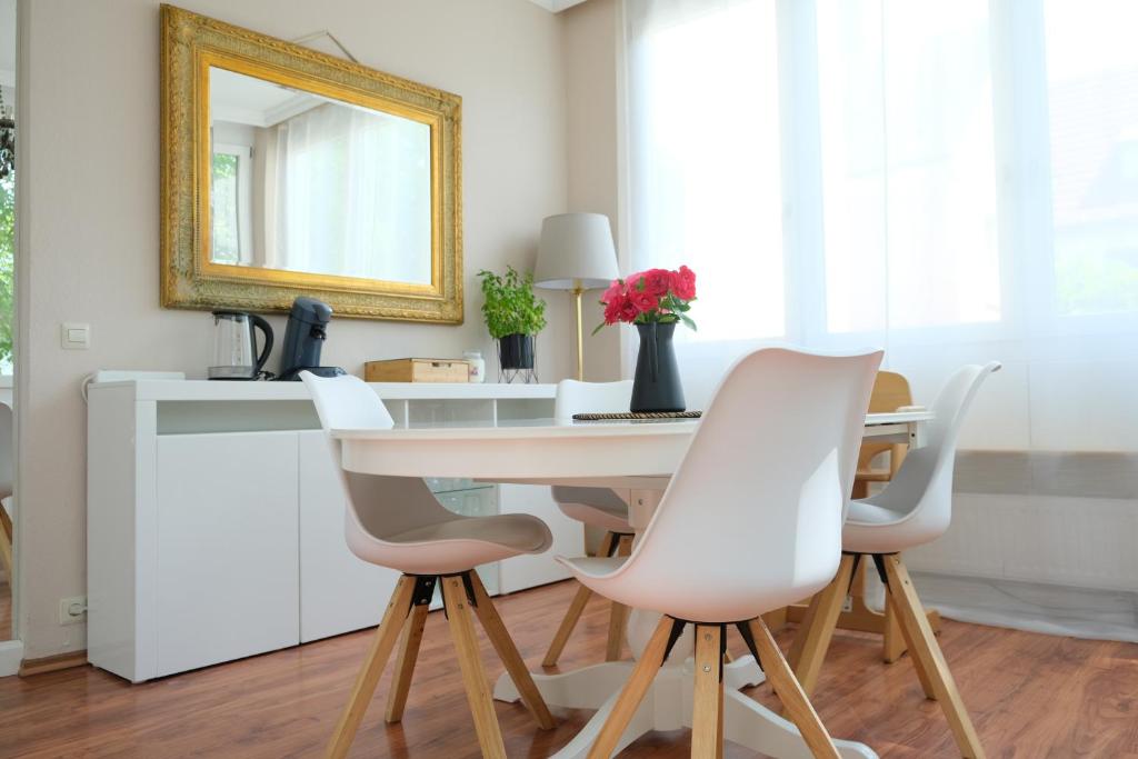a white dining room table with white chairs and a mirror at CasaLuxe: Familienfreundliche 115m² in der Stadtmitte in Günzburg
