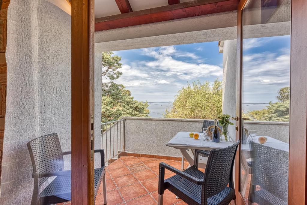eine Terrasse mit Tisch und Stühlen auf einem Balkon in der Unterkunft Valdarke Sea View Apartment - Happy Rentals in Mali Lošinj