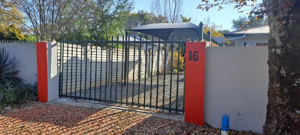 una recinzione con un cancello con un albero di The Cottage Unit a Bloemfontein