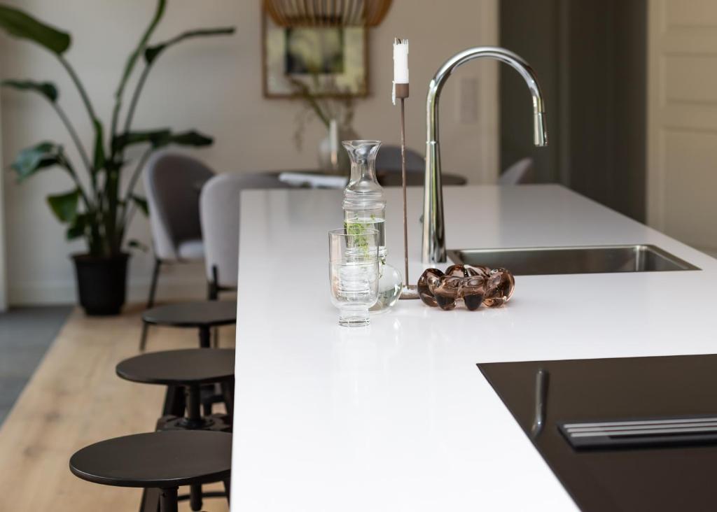 um balcão de cozinha com um lavatório e uma garrafa de vidro em Halltorp Townhouse em Borgholm