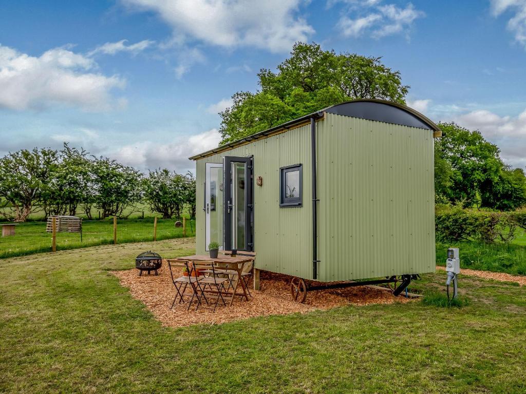 a green tiny house with a table in a field at Foxglove - Uk37639 in Bradbourne