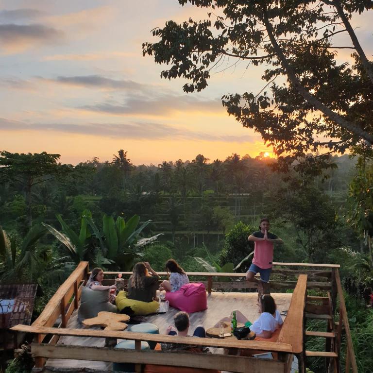 a group of people sitting in a hot tub with the sunset in the background at Tetebatu Sama Sama Bungalows in Tetebatu