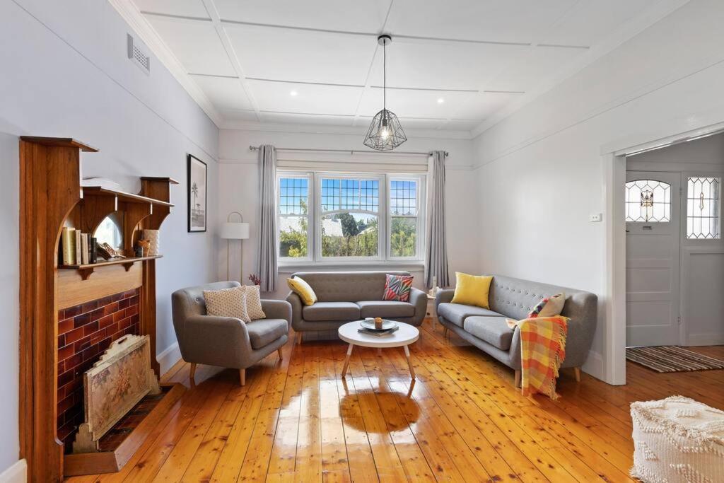 a living room with two couches and a fireplace at Mid Century 1930 Beautifully renovated Californian Bunglow in Newtown and Chilwell