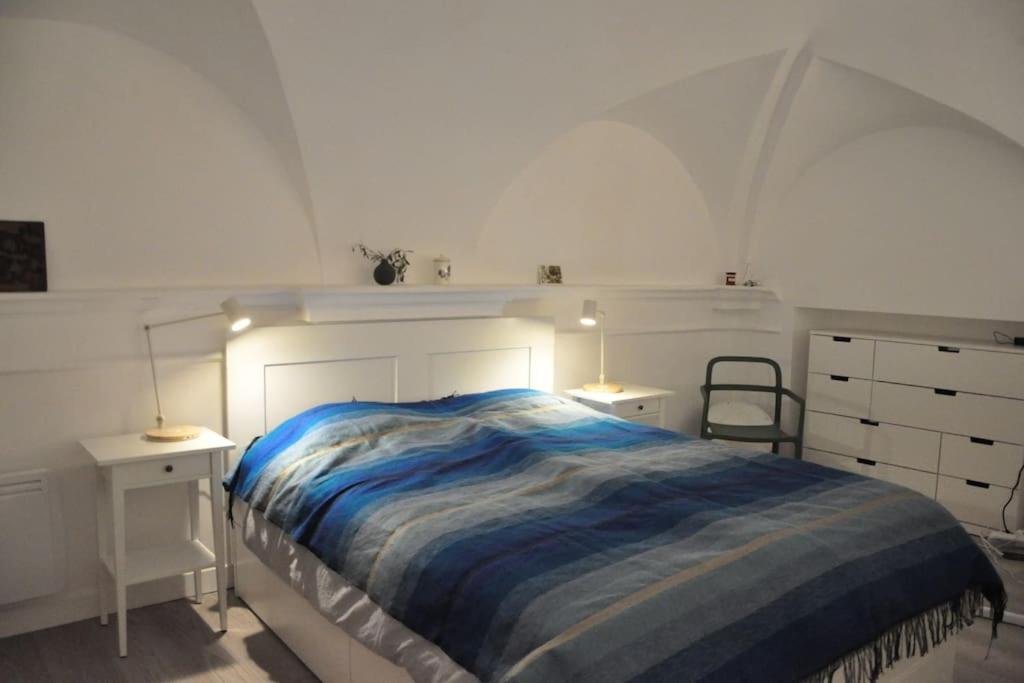 a white bedroom with a bed and two night stands at Unique apartment in the old town, near the beach in Menton