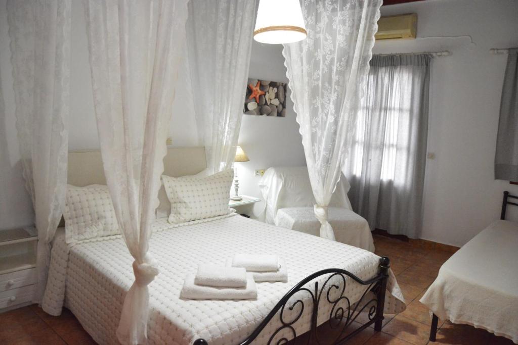 a bedroom with a white bed with white curtains at Stefanos Katsaros Studios in Skala