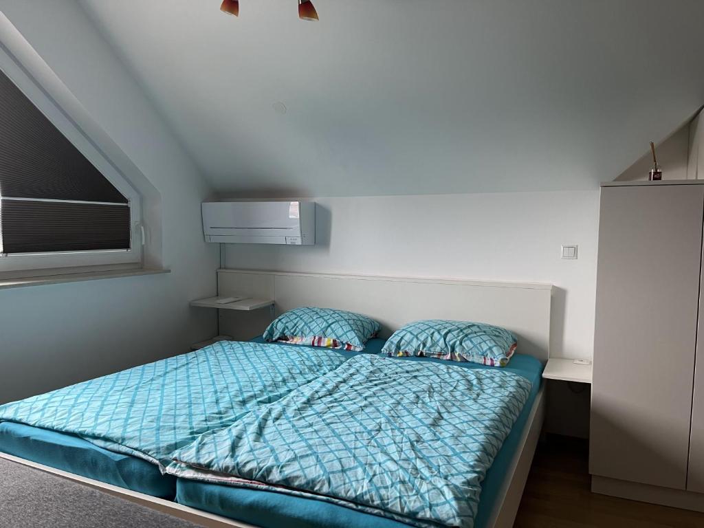um pequeno quarto com uma cama com um edredão azul em Apartma Ajda 2 , Jezerska cesta 65, Kranj em Kranj