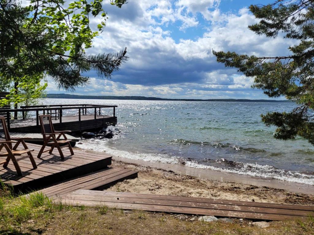 a dock with a bench and chairs on the beach at Lakeland Karelia Puutikka in Kesälahti