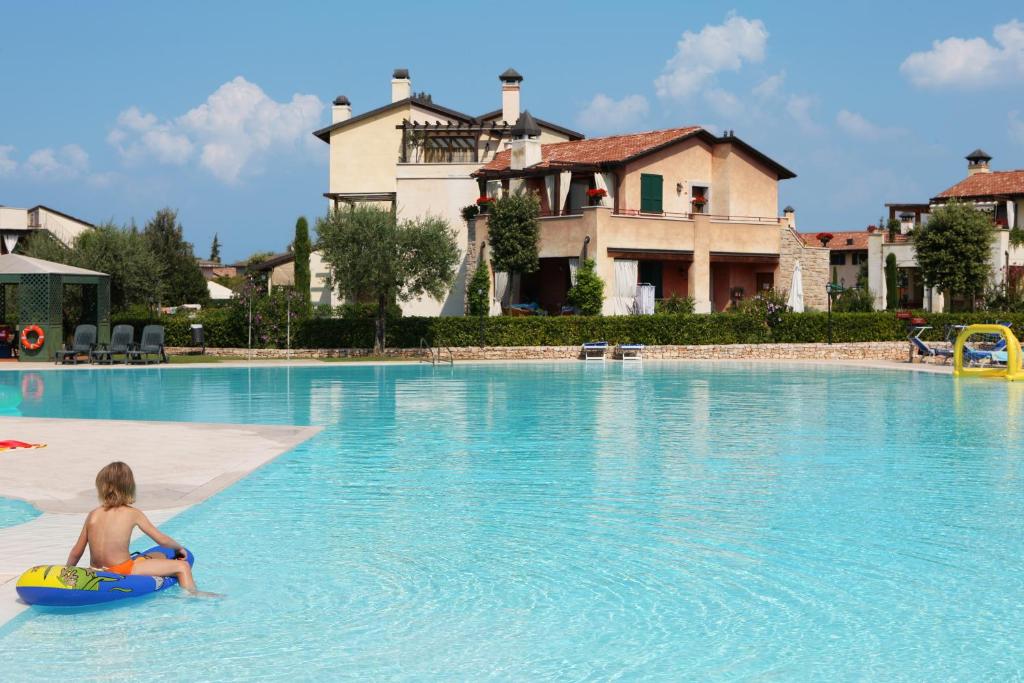 un niño pequeño sentado en una balsa en una piscina en Garda Resort Village, en Peschiera del Garda