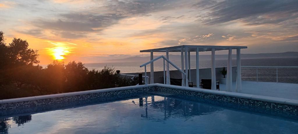 a swimming pool with a sunset in the background at Holiday home Ivo in Prigradica