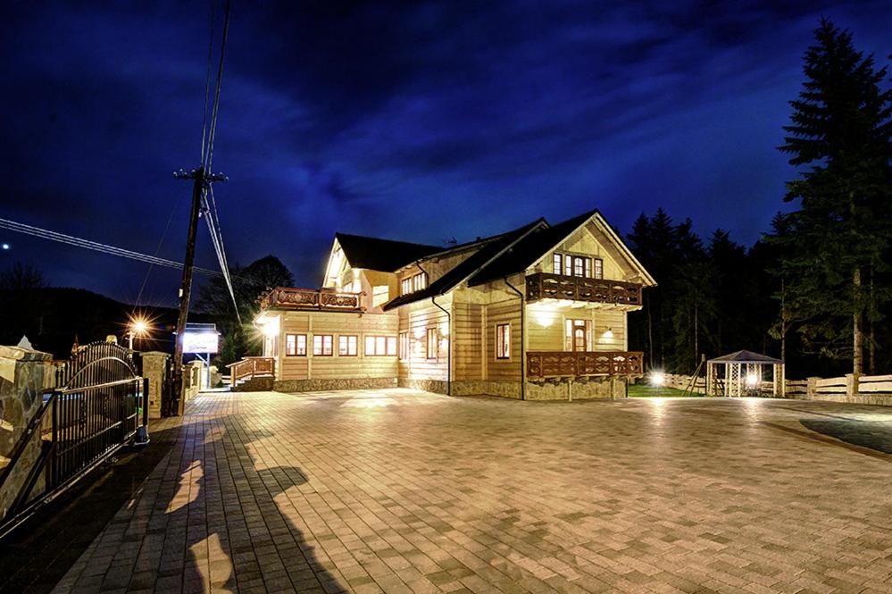 a house with lights on in a parking lot at night at Noclegi Styrnol & SPA in Zawoja