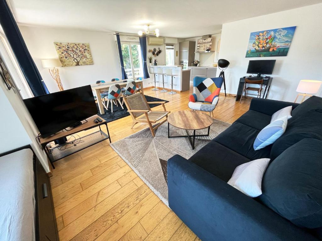 a living room with a blue couch and a tv at Appartement 84m² avec 2 parkings privatifs in Villeneuve-Loubet