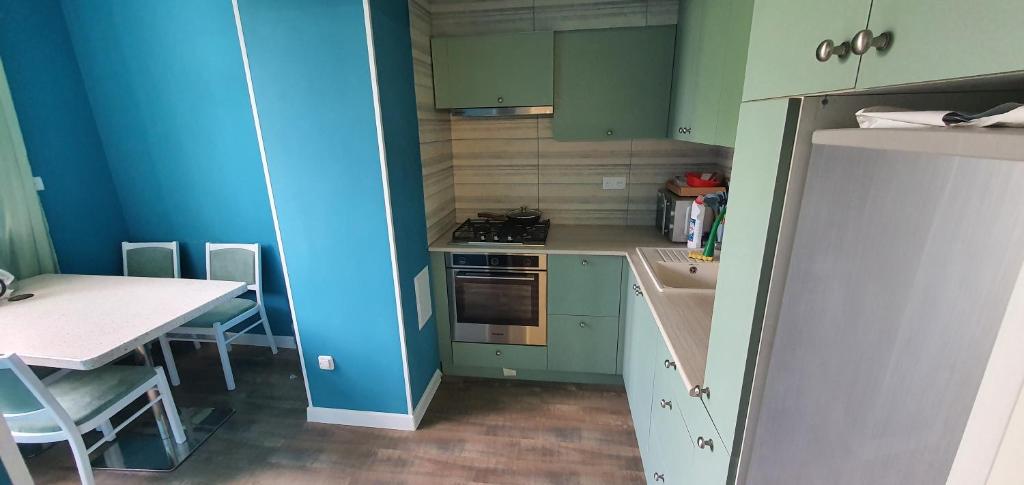 a kitchen with green cabinets and a table and a blue wall at Марказ_5 in Tashkent