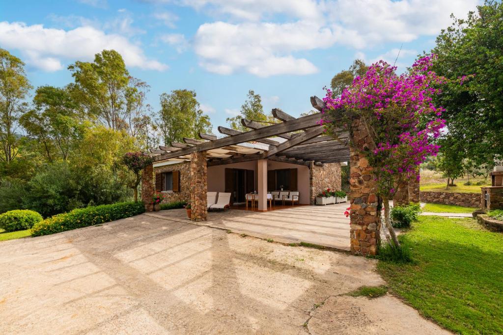 a wooden pergola in a garden with pink flowers at Casa Suestellas 